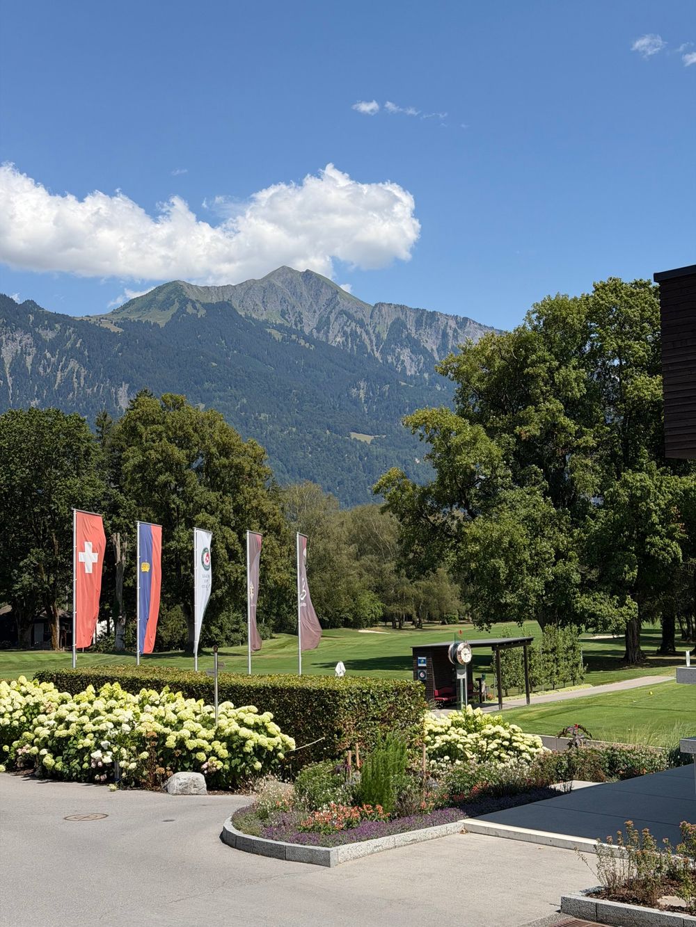Swiss and Liechtenstein flags in front of a golf course and a mountain in Bad Ragaz
