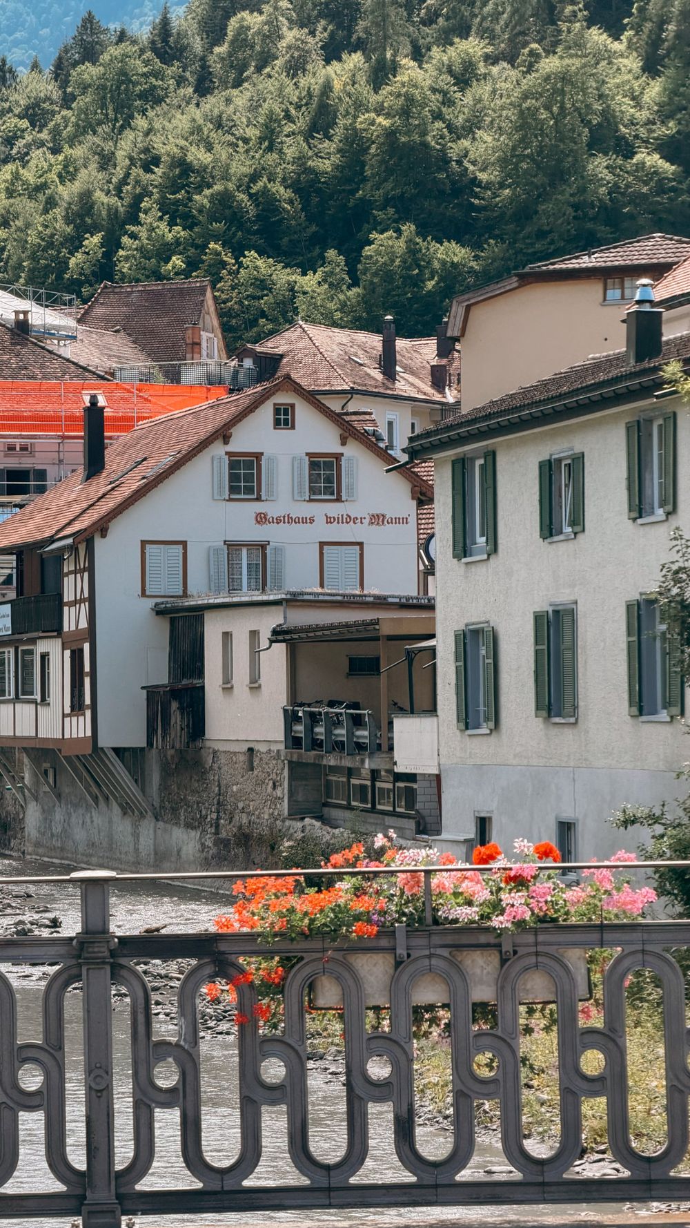 Old houses along the Tamina river in Bad Ragaz, with flowers on a bridge