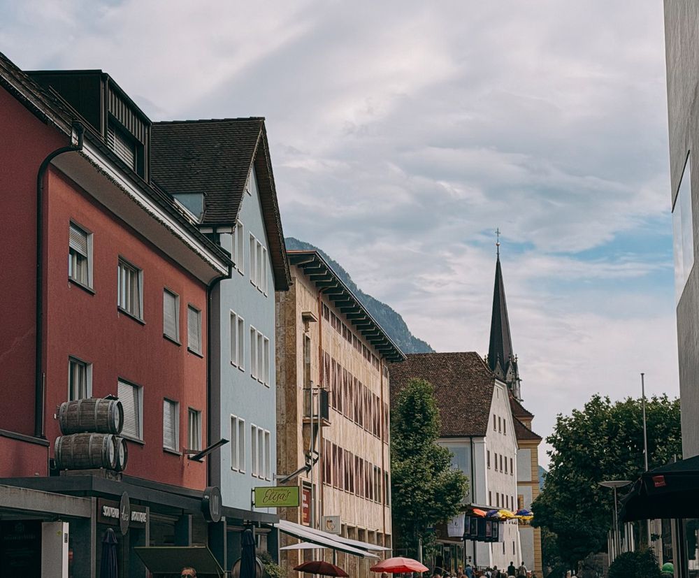 Colourful houses on the pedestrian street of Vaduz, with the cathedral spire
